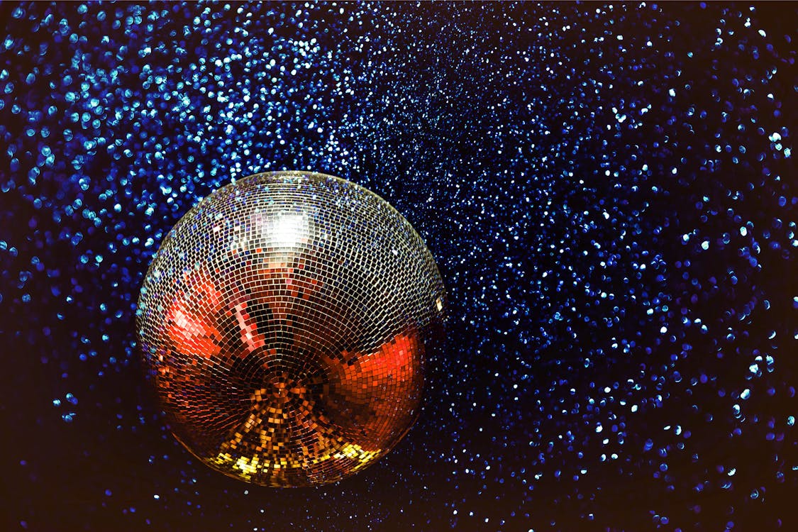 A disco ball casting scattered light against a dark background, evoking the celebratory energy of New Year’s Eve